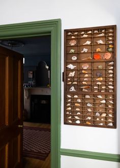 an open door leading to a room with shells on the wall and green trimming