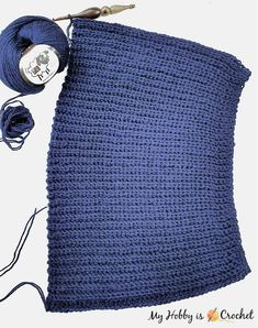 a blue crochet blanket with two skeins of yarn next to it