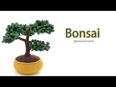 a small crocheted bonsai tree sitting on top of a yellow pot filled with green leaves