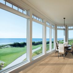 a large open living room with lots of windows overlooking the ocean and golf course in the distance