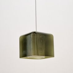 a green light hanging from a ceiling in a room with white walls and flooring