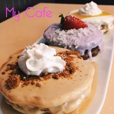 three desserts on a white plate with whipped cream and strawberries in the background