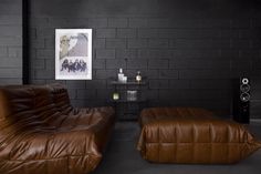 a living room with two brown leather couches and speakers on either side of the wall