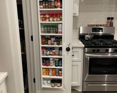 an open pantry door in a kitchen with stainless steel stove top oven and white cabinets