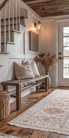 a wooden bench sitting in front of a white door next to a rug on top of a hard wood floor