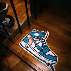 a blue and white sneaker sticker sitting on top of a wooden floor next to a mirror