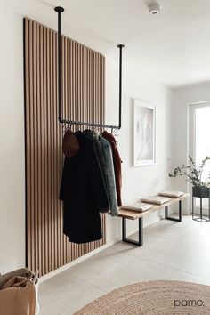 a coat rack with clothes hanging on it in front of a wall mounted coat rack