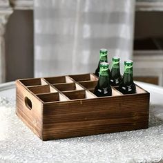 four beer bottles in a wooden crate sitting on a white tablecloth covered table top