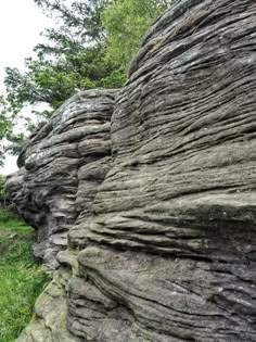 some very large rocks with grass and trees in the background