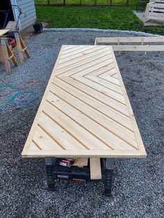 a wooden table sitting on top of a gravel field next to a fence and building materials