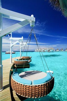 two hammock chairs sitting on top of a wooden pier