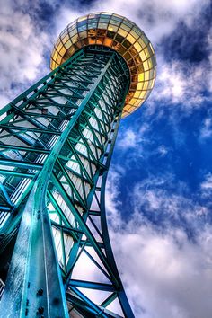 a tall metal structure with a sky background and clouds in the backgrouund