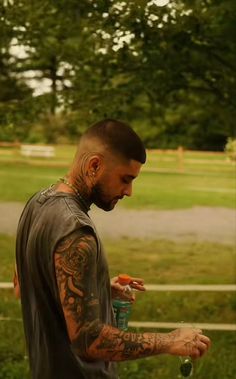 a man with tattoos on his arm holding a cup