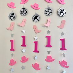 pink and silver decorations are hanging on the wall in front of a white wall with stars