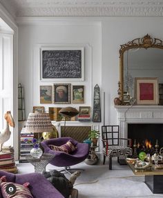 a living room filled with furniture and a fire place in front of a mirror on the wall