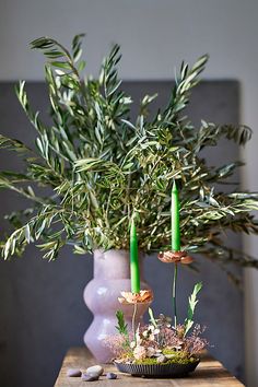 a vase with two candles and some plants in it