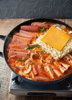 a pan filled with meat, noodles and cheese on top of an electric burner