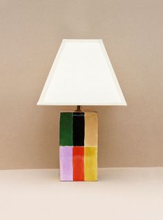 a multicolored lamp with a white shade on it