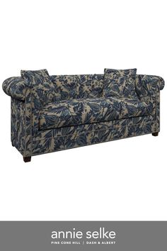 an image of a couch that is blue and white with leaves on the back, sitting in front of a white background