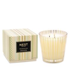 a glass candle sitting next to a box on a white surface with the words nest printed on it