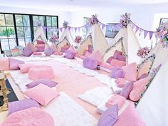 a room filled with lots of pillows covered in pink and purple blankets on the floor