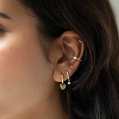 a woman wearing gold ear cuffs with two small hearts on the end of each ear