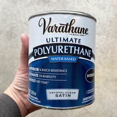 a person holding up a can of water based vartahane paint in their hand