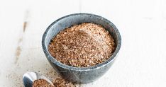 a bowl filled with brown sugar next to a spoon on top of a white table