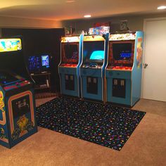 two arcade machines sitting next to each other on top of a carpeted floor in front of a doorway