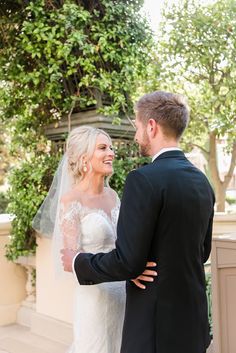 a bride and groom standing together in front of some trees