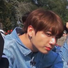 a young man with ear buds on his ears is looking at the camera while wearing a denim jacket