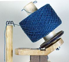 a spool of blue yarn sitting on top of a wooden block