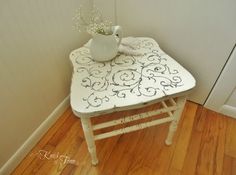 a small white table with a vase on top