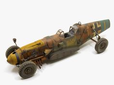 an old model airplane with wheels and tires on a white surface, it is painted in camouflage