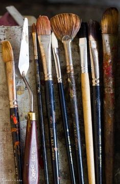 an assortment of paint brushes lined up on a table