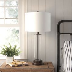 a bedroom with a bed, nightstand and lamp next to a window on the wall