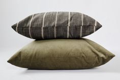 two pillows stacked on top of each other in front of a white background with black and grey stripes