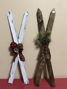 two wooden skis are decorated with pine cones and plaid bow ties, one is hanging on the wall