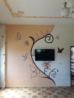 a television mounted to the side of a wall in a living room with butterflies painted on it