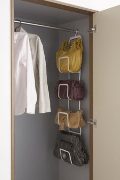 an open closet with several purses and handbags hanging on the wall next to it