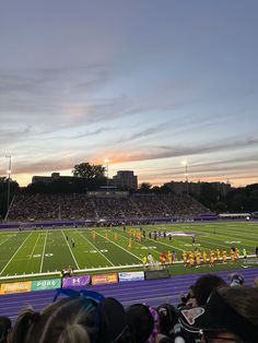 a football game is being played on an empty field at dusk with the sun setting