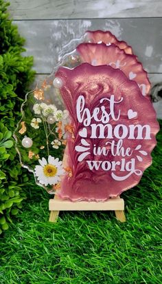 the best mom in the world award is displayed on green grass with daisies and flowers