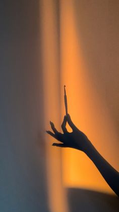 a person's hand reaching out towards the light coming in from behind them on a wall