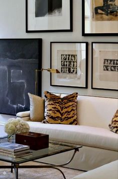 a living room filled with furniture and framed pictures on the wall above it's coffee table