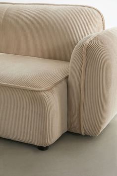 a beige couch sitting on top of a hard wood floor next to a white wall