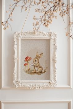 a white frame hanging on the wall with a rabbit and mushroom in it