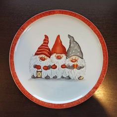 an orange and white plate with three gnomes on it