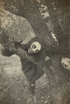 an old photo of a creepy doll hanging from a tree