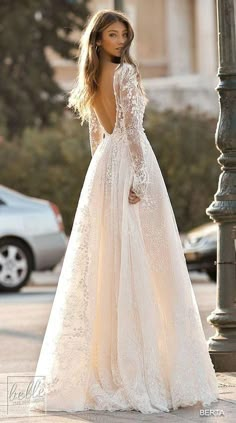 a woman in a wedding dress standing next to a lamp post and looking back at the camera