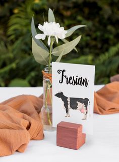 there is a card with a cow on it next to a flower in a vase